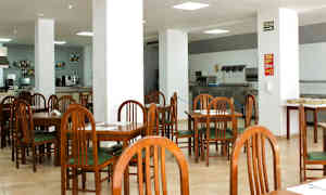 En café eller restaurant med træstole og borde samt hvide søjler i et stort åbent område. (AI-genereret tekst)