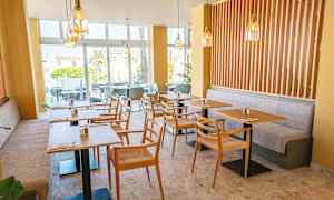 En moderne café med borde og stole samt lyse farver. (AI-genereret tekst)