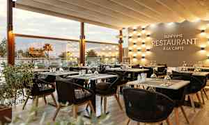 Solbeskinnet restaurantmiljø med elegant oppsatte borde og stole. (AI-genereret tekst)