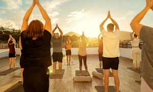 En gruppe mennesker udfører yogapositioner på en udendørsplatform ved solnedgang. (AI-genereret tekst)