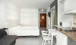 Et hotelværelse med en dobbeltseng, en sofa, spisebord med stole og et tekøkken. (AI-genereret tekst)