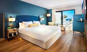 Hotelværelse med dobbeltseng, siddeplads og udsigt over havet. (AI-genereret tekst)