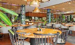 Interiør af en restaurant med træborde, stole og grønne dekorationer. (AI-genereret tekst)