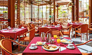 En restaurant med borde dækket med røde duge, serverer morgenmad inklusive kaffe, juice og bagværk. (AI-genereret tekst)