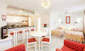 Værelse med to enkeltsenge, siddeområde og køkkenområde. (AI-genereret tekst)