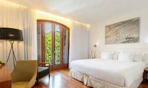 Et lyst hotelværelse med en stor seng, træmøbler og en balkon med udsigt. (AI-genereret tekst)