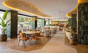 En elegant restaurant med moderne møbler og indretning, beliggende indendørs med grønne detaljer og stor bar i baggrunden. (AI-genereret tekst)