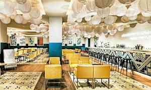 En moderne og indbydende restaurant med gule lænestole, dekorative lanterner i loftet og en stilfuld bar. (AI-genereret tekst)