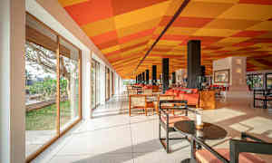 Et lyst og rummeligt rum med glasvægge, farverigt mønster på loftet og moderne siddepladser. (AI-genereret tekst)