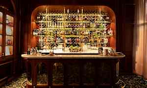 En elegant bar med flasker på hylder bag en marmordisk. (AI-genereret tekst)