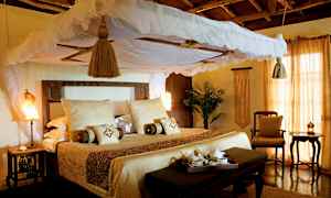 En indbydende seng med baldakin og lyse tekstiler i et rustikt indrett rum. (AI-genereret tekst)