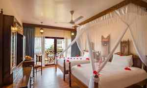 Hotelværelse med to senge, dekoreret med myggenet og røde blomsterblade. (AI-genereret tekst)