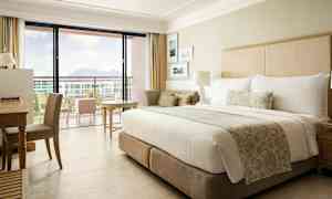 Et hotelværelse med en stor seng, skrivebord og en balkon med udsigt. (AI-genereret tekst)