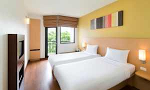 Et hotelværelse med to enkeltsenge, lyse vægge og et vindue. (AI-genereret tekst)