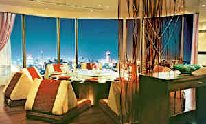 En elegant spisestue med panoramaudsigt over en oplyst by om aftenen. (AI-genereret tekst)