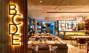 Et moderne restaurantområde med belysning, siddepladser og en bardisk. (AI-genereret tekst)