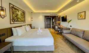 Moderne indrettet hotelværelse med dobbeltseng, sofa og arbejdsområde. (AI-genereret tekst)