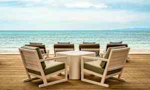 Træmøbler på en terrasse med udsigt over havet. (AI-genereret tekst)