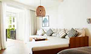 En stue med en hjørnesofa, puder og glasdøre, der fører til en terrasse. (AI-genereret tekst)