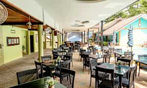 En udendørs restaurant med borde og stole ved en swimmingpool. (AI-genereret tekst)