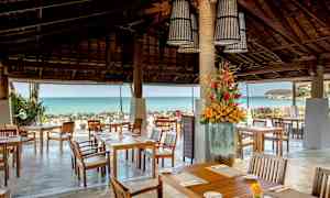 Udendørs spiseområde med siddepladser, blomsterdekoration og havudsigt. (AI-genereret tekst)