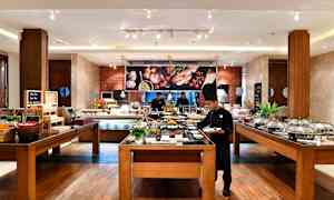 Buffetområde i en restaurant med madstationer og siddepladser. (AI-genereret tekst)