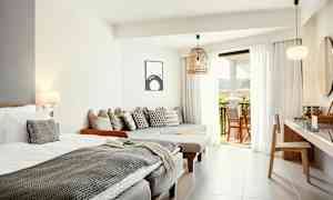 Lyse og moderne hotelværelse med seng, siddepladser og åbning til balkon. (AI-genereret tekst)