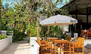 Havemøbler under en stribet parasol i en frodig omgivelser. (AI-genereret tekst)