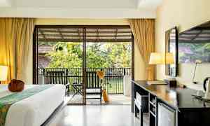 Et hotelværelse med en seng, skrivebord og en altan med udsigt over haven. (AI-genereret tekst)