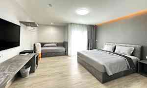 Et hotelværelse med en dobbeltseng, en sofa og et TV på væggen. (AI-genereret tekst)