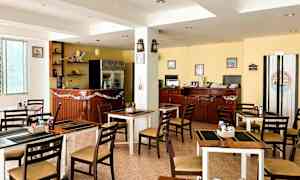 Et billede af en lille restaurant eller café med borde og stole, en bardisk og interiør inklusive pyntegenstande og dekorationer. (AI-genereret tekst)