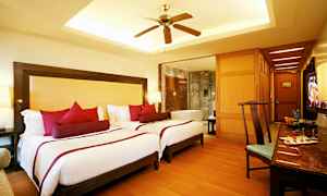 Et hotelværelse med to enkeltsenge, en ventilator og et badekar i baggrunden. (AI-genereret tekst)