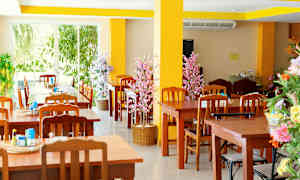 Restaurant med træborde og stole samt dekorative blomster. (AI-genereret tekst)