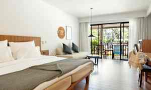 Et hotelværelse med en dobbeltseng, sofa og altan med udsigt. (AI-genereret tekst)