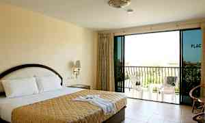 Et hotelværelse med en dobbeltseng, natbord, glasdøre og en balkon med stole. (AI-genereret tekst)