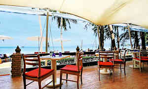 Siddepladser ved et bord under en markise med udsigt over stranden og havet. (AI-genereret tekst)