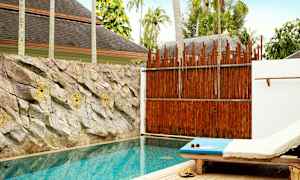 En privat pool med solseng ved siden og sten pryder væggen bag poolen. (AI-genereret tekst)