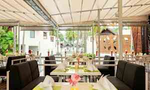 Udendørs serveringsområde med bord og stole dækket op under tag. (AI-genereret tekst)