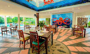 Restaurant med træmøbler, farverige vægmalerier med havtema, og en pool i baggrunden. (AI-genereret tekst)