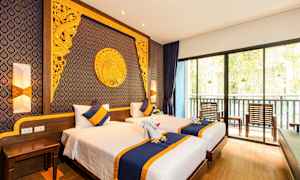 Et hotelværelse med to enkeltsenge, dekoreret med blåt og gult sengetøj og puder. Væggen bag sengene er dekoreret med indviklede gyldne mønstre og design. Et stort vindue for enden viser en altan med stole og udsigt over vegetation. (AI-genereret tekst)
