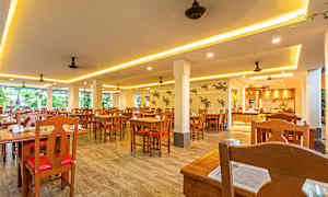 Billede af en lys restaurant med træborde og -stole. (AI-genereret tekst)