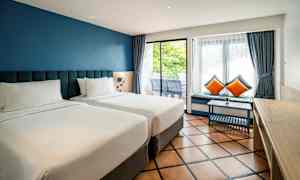 To enkeltsenge i et hotelværelse med blå vægge og store vinduer. (AI-genereret tekst)