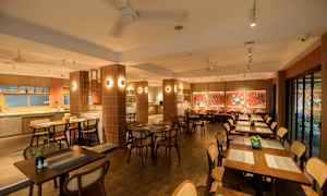 En restaurant med træborde og stole, dekoreret med røde vægge og kunstværker. (AI-genereret tekst)