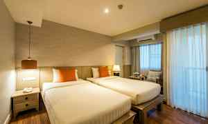 To enkeltsenge med orange puder i et rum med trædetaljer og gardiner, der lukker lys ind. (AI-genereret tekst)