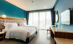 Hotelværelse med to enkeltsenge, skrivebord, TV og store vinduer. (AI-genereret tekst)