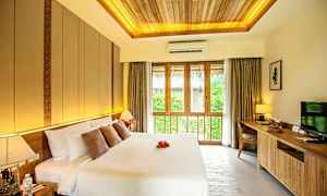 Et soveværelse med en stor dobbeltseng, dekorative puder og en sengelampe. Et stort vindue med gardiner lukker naturligt lys ind. (AI-genereret tekst)