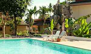 Udendørs pool omgivet af tropiske træer og en dekorativ stenstatue. (AI-genereret tekst)