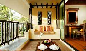 En udendørs terrasse med en sofa dekoreret med puder, et lille bord med frugt og tallerkener og udsigt til grønne områder. (AI-genereret tekst)