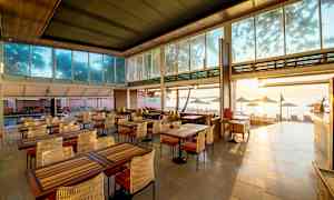 En restaurant med udsigt over stranden, møbleret med borde og stole. (AI-genereret tekst)