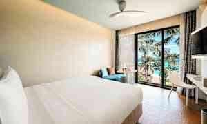 Moderne hotelværelse med udsigt over hav og palmer gennem et vindue. (AI-genereret tekst)